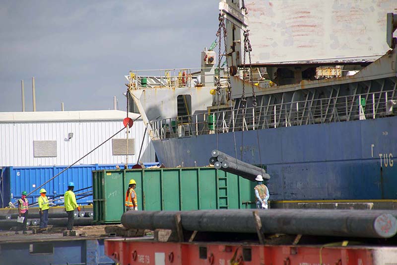 port freeport employees in hard hats walking near a dumpster bin